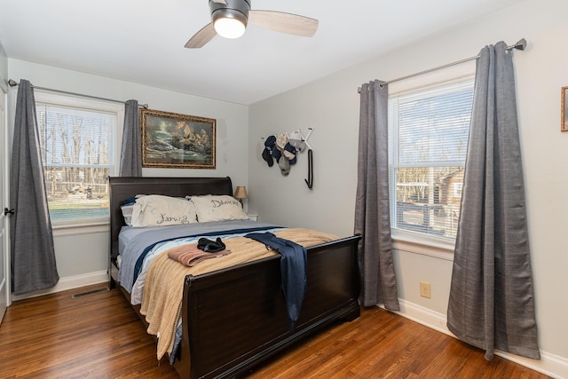 bedroom featuring dark hardwood / wood-style flooring, multiple windows, and ceiling fan