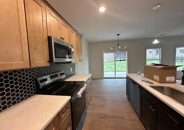 kitchen featuring decorative light fixtures, tasteful backsplash, light hardwood / wood-style floors, sink, and stainless steel appliances