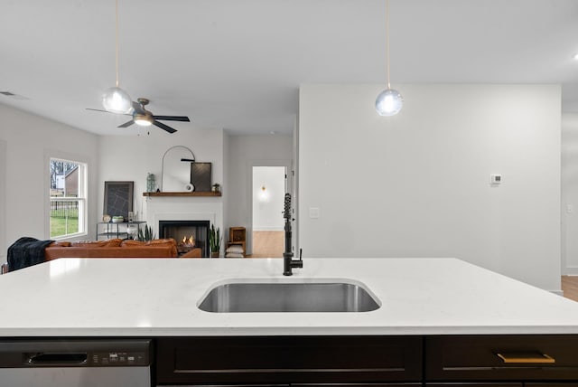 kitchen with sink, decorative light fixtures, a center island with sink, stainless steel dishwasher, and light stone countertops