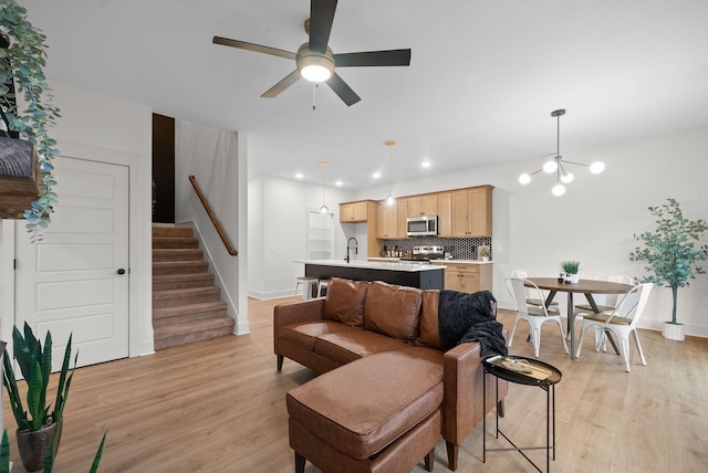 living room featuring ceiling fan with notable chandelier and light hardwood / wood-style floors