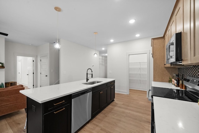 kitchen featuring pendant lighting, sink, stainless steel appliances, a center island, and light wood-type flooring