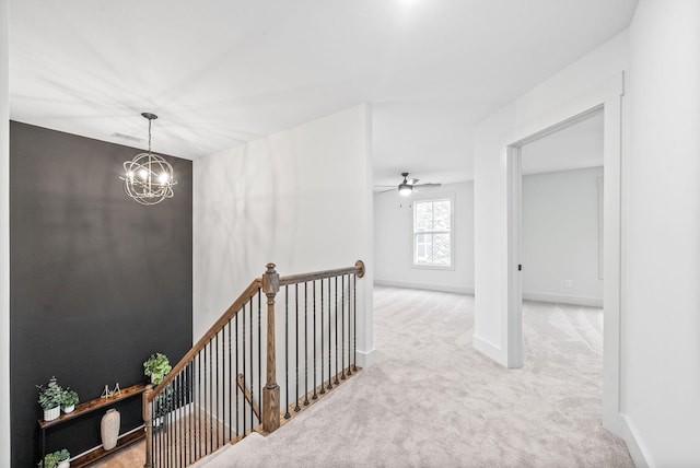 hallway with light colored carpet and an inviting chandelier