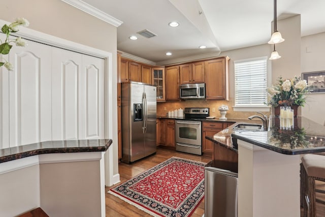 kitchen with sink, a kitchen breakfast bar, kitchen peninsula, hanging light fixtures, and appliances with stainless steel finishes