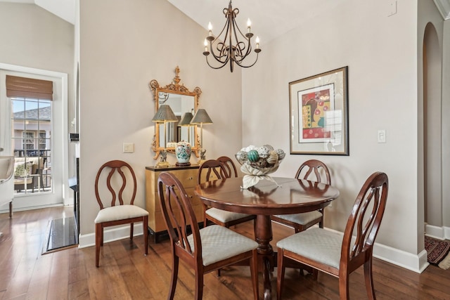 dining area with dark hardwood / wood-style flooring, an inviting chandelier, and vaulted ceiling