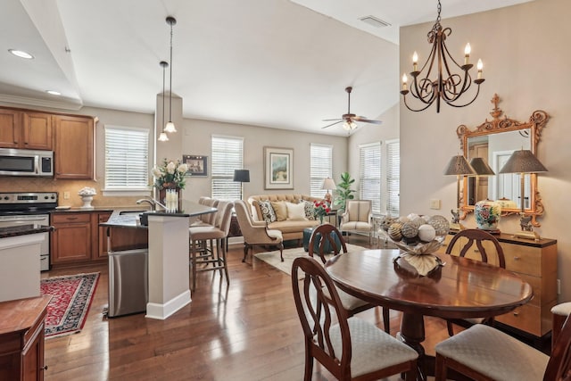 dining space featuring sink, dark wood-type flooring, vaulted ceiling, and ceiling fan with notable chandelier