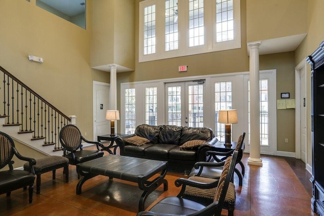 living room featuring a towering ceiling, french doors, and ornate columns