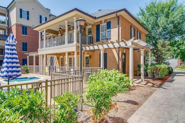 exterior space featuring a balcony, ceiling fan, and a pergola