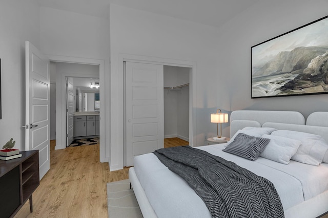 bedroom with light hardwood / wood-style floors, a walk in closet, ensuite bathroom, and a closet