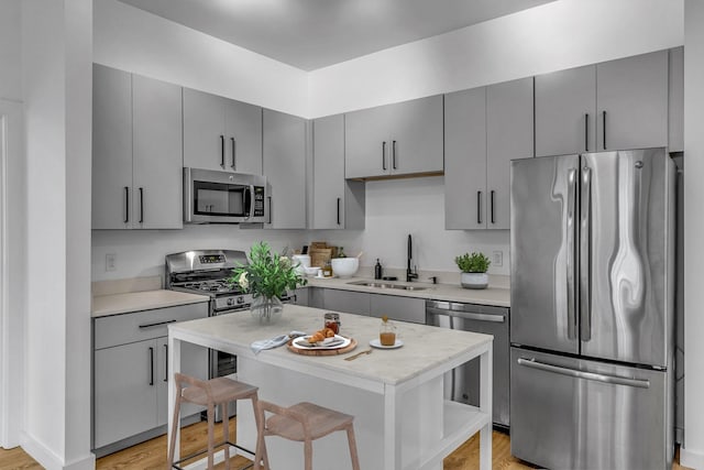 kitchen featuring appliances with stainless steel finishes, light hardwood / wood-style flooring, a kitchen island, and sink