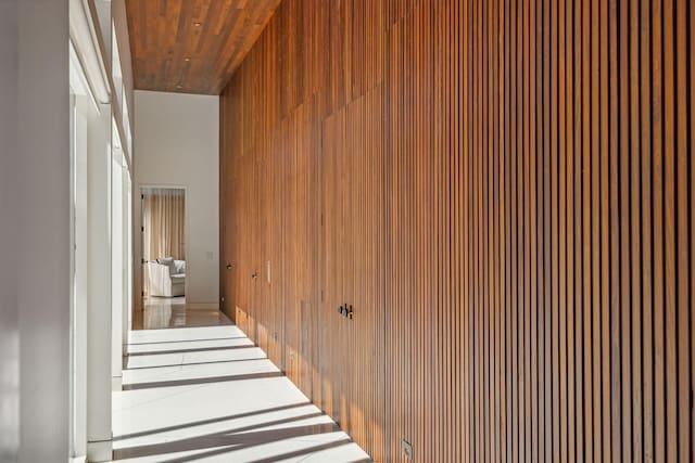 hall with a high ceiling, wood walls, and wooden ceiling