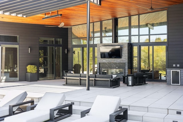 view of patio / terrace featuring ceiling fan and an outdoor living space with a fireplace