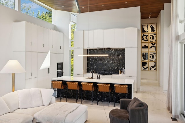 tiled living room with a towering ceiling, sink, and wood ceiling