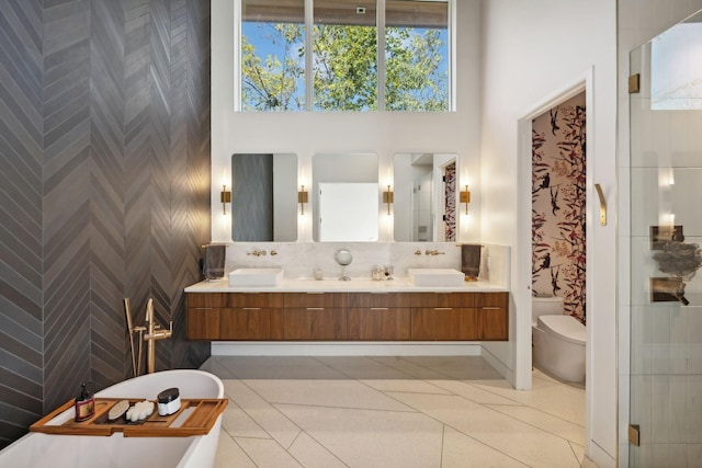 bathroom featuring toilet, tile patterned flooring, a tub to relax in, a towering ceiling, and vanity