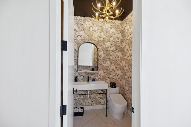 bathroom with toilet, tile patterned floors, sink, and a notable chandelier