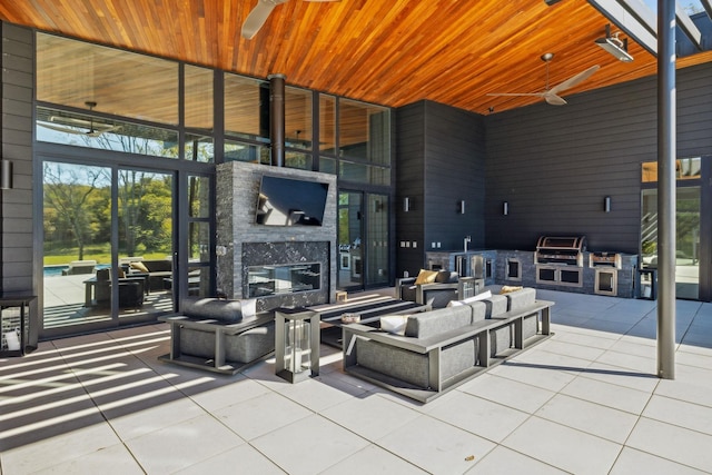 view of patio / terrace featuring exterior kitchen, ceiling fan, and an outdoor living space with a fireplace