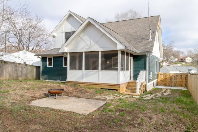 back of property with a fire pit, a sunroom, and a patio area