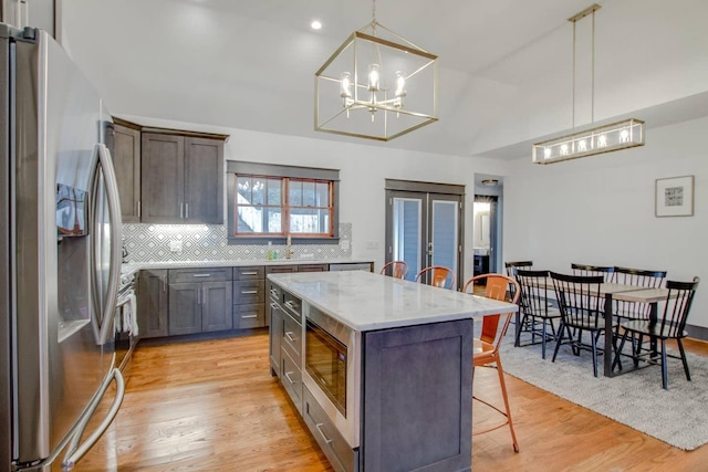 kitchen with stainless steel fridge with ice dispenser, a center island, built in microwave, a kitchen bar, and decorative light fixtures