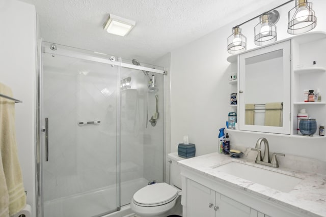 bathroom featuring toilet, vanity, a textured ceiling, and a shower with shower door