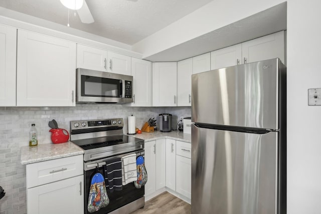 kitchen featuring stainless steel appliances, light wood-type flooring, white cabinets, and decorative backsplash