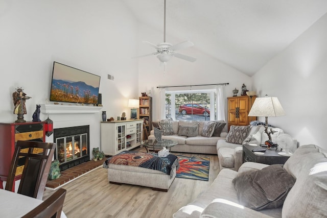 living room with a fireplace, high vaulted ceiling, ceiling fan, and hardwood / wood-style floors