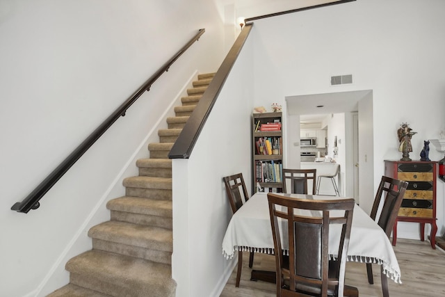 dining space featuring a high ceiling and light hardwood / wood-style flooring