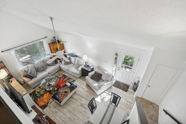 living room with a textured ceiling, light hardwood / wood-style floors, and lofted ceiling