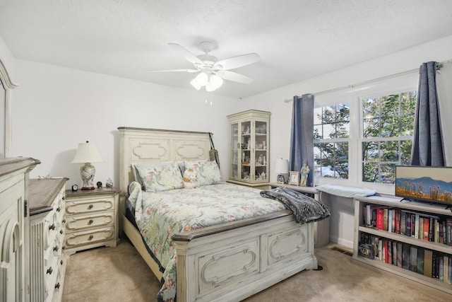 bedroom with light carpet, ceiling fan, and a textured ceiling