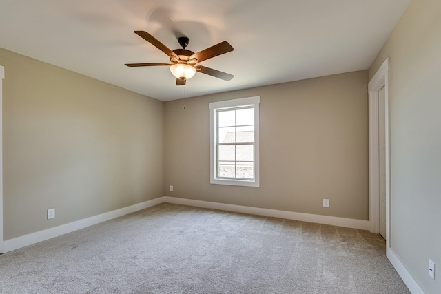 spare room with ceiling fan and light colored carpet