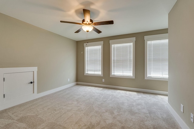 spare room with light colored carpet, ceiling fan, and a healthy amount of sunlight