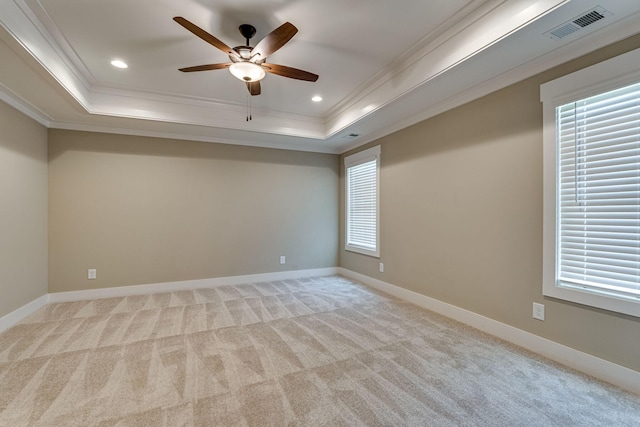 carpeted spare room featuring a raised ceiling, ceiling fan, and crown molding