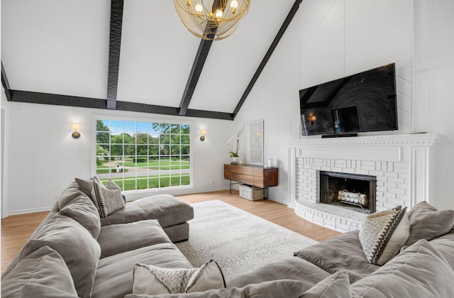 living room with a chandelier, light hardwood / wood-style floors, high vaulted ceiling, a fireplace, and beamed ceiling