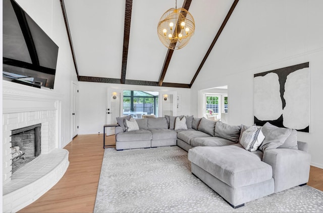 living room with beamed ceiling, hardwood / wood-style floors, an inviting chandelier, and a fireplace