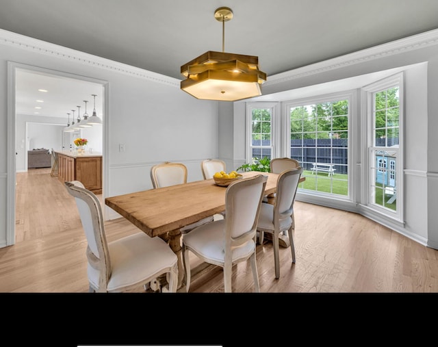 dining area with light wood-type flooring, ornamental molding, and plenty of natural light