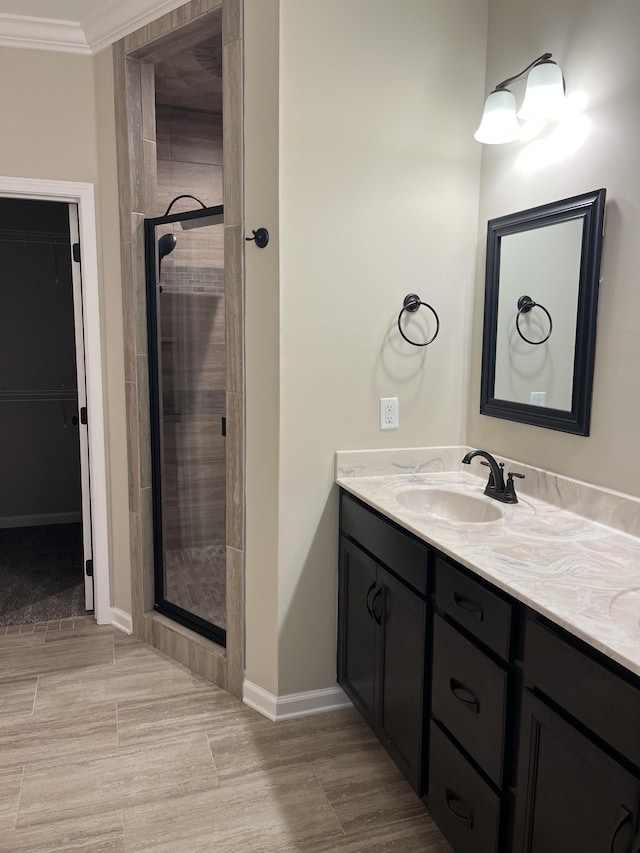 bathroom featuring vanity, a shower with shower door, and crown molding