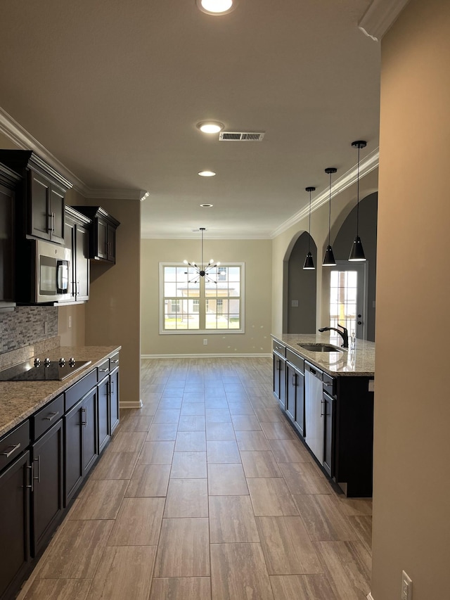 kitchen with sink, pendant lighting, light stone counters, and stainless steel appliances