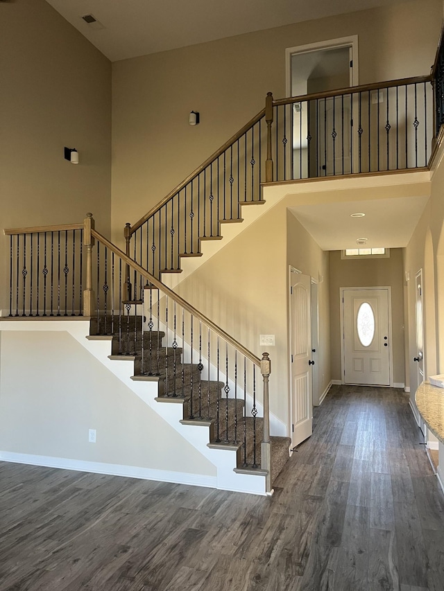 entrance foyer featuring a towering ceiling and dark wood-type flooring