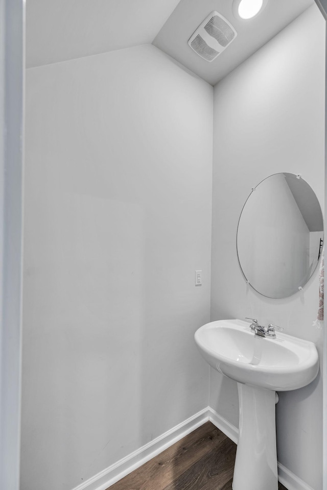 bathroom featuring sink, hardwood / wood-style floors, and lofted ceiling