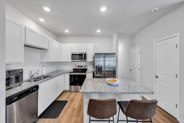 kitchen with a kitchen island, stainless steel appliances, white cabinets, and sink