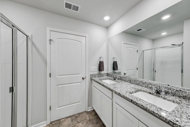 bathroom featuring a shower with shower door and vanity