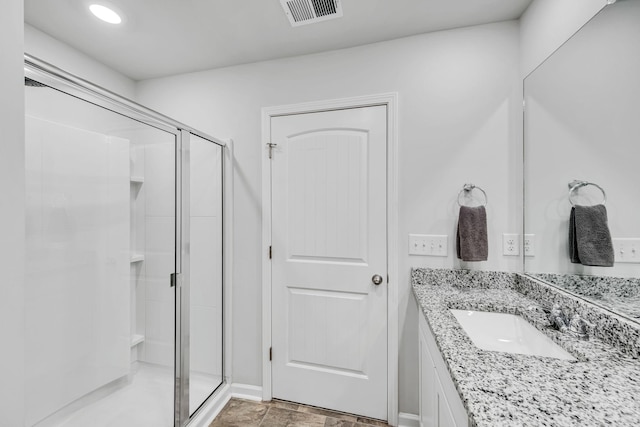 bathroom featuring a shower with door and vanity