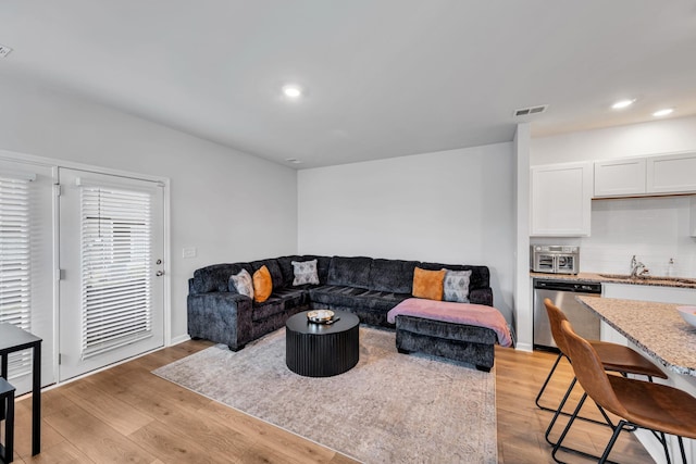 living room featuring sink and light hardwood / wood-style flooring