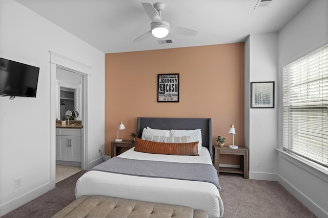 carpeted bedroom with ceiling fan, ensuite bathroom, and multiple windows