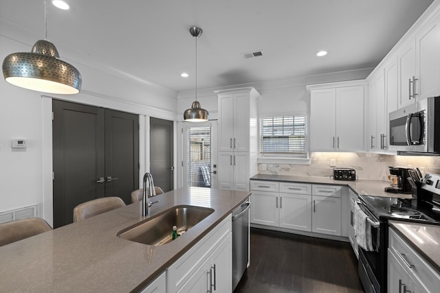 kitchen with appliances with stainless steel finishes, decorative light fixtures, sink, and white cabinets