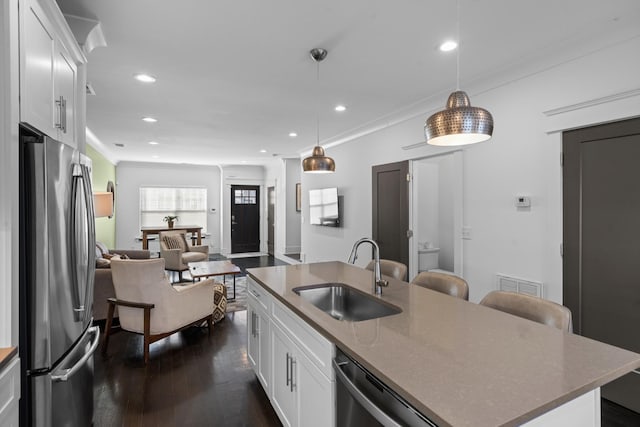 kitchen with white cabinetry, sink, stainless steel fridge, and an island with sink