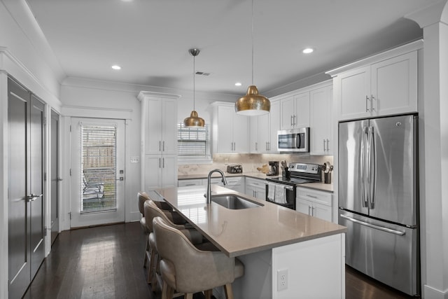 kitchen with pendant lighting, sink, white cabinets, a kitchen island with sink, and stainless steel appliances