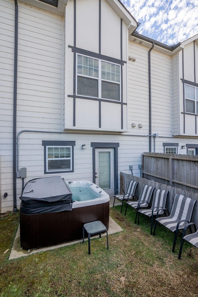 rear view of property with a yard and a hot tub