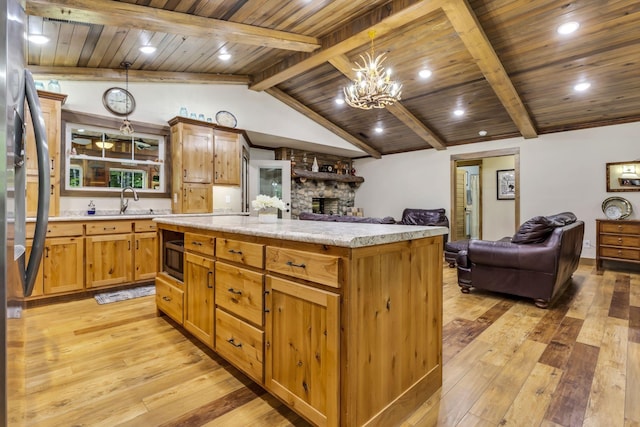 kitchen with a center island, a fireplace, vaulted ceiling with beams, light hardwood / wood-style flooring, and a chandelier