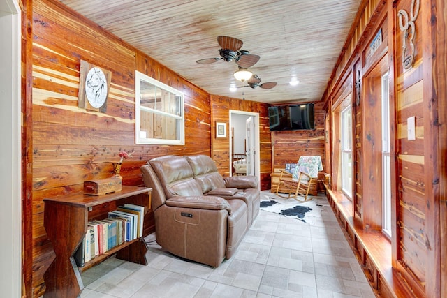 living area featuring ceiling fan, wooden ceiling, and wooden walls