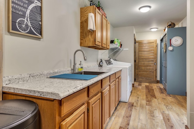 kitchen featuring light wood-type flooring, washing machine and dryer, and sink