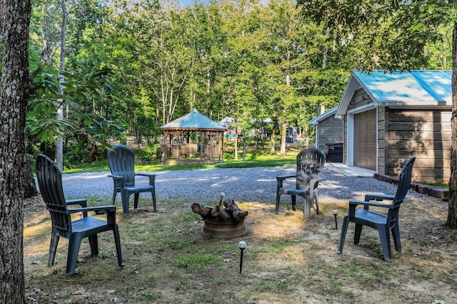 view of yard with a gazebo, an outbuilding, a garage, and a fire pit